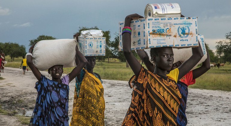 Women carry food assistance received at a WFP emergency distribution point in Thaker, Unity state, South Sudan.