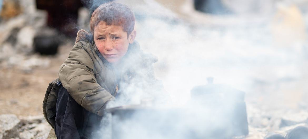 A displaced 10-year-old boy uses heat from a wood stove to stay warm during the harsh winter in Herat province, Afghanistan. 