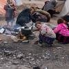 在阿富汗寒冷的冬天，孩子们利用柴火炉的热量取暖。