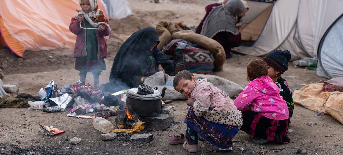在阿富汗寒冷的冬天，孩子们利用柴火炉的热量取暖。