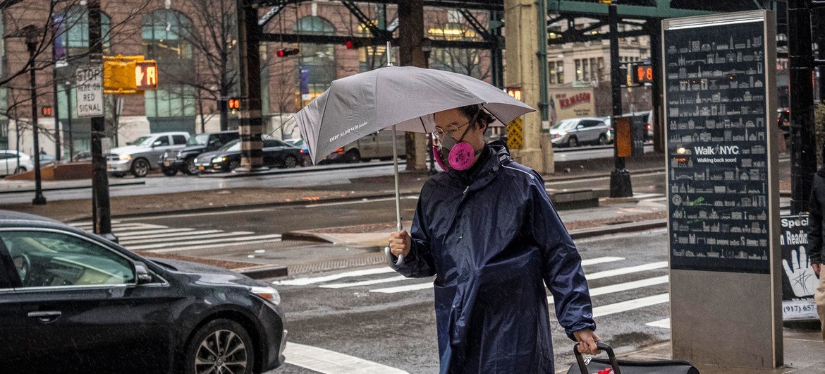 A man wearing a face mask to prevent infection by the COVID-19 virus walks on the streets of a semi-deserted New York City.