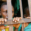 Two young prisoners stand behind bars in a jail in Abomey, Benin.