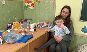 A mother who fled Bucha with her family sits with her son at their current refuge in Zakarpattia, Ukraine.