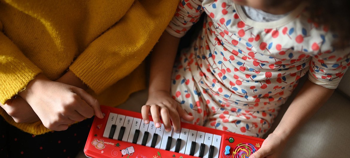 Una madre y su hija tocan un teclado mientras están en confinadas en casa durante la pandemia COVID-19.