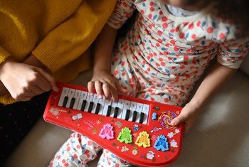 A mother and daughter play a keyboard while staying at home during the COVID-19 pandemic.
