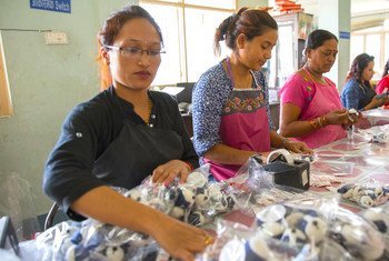 Women work in an assembly line to package handicrafts for export.