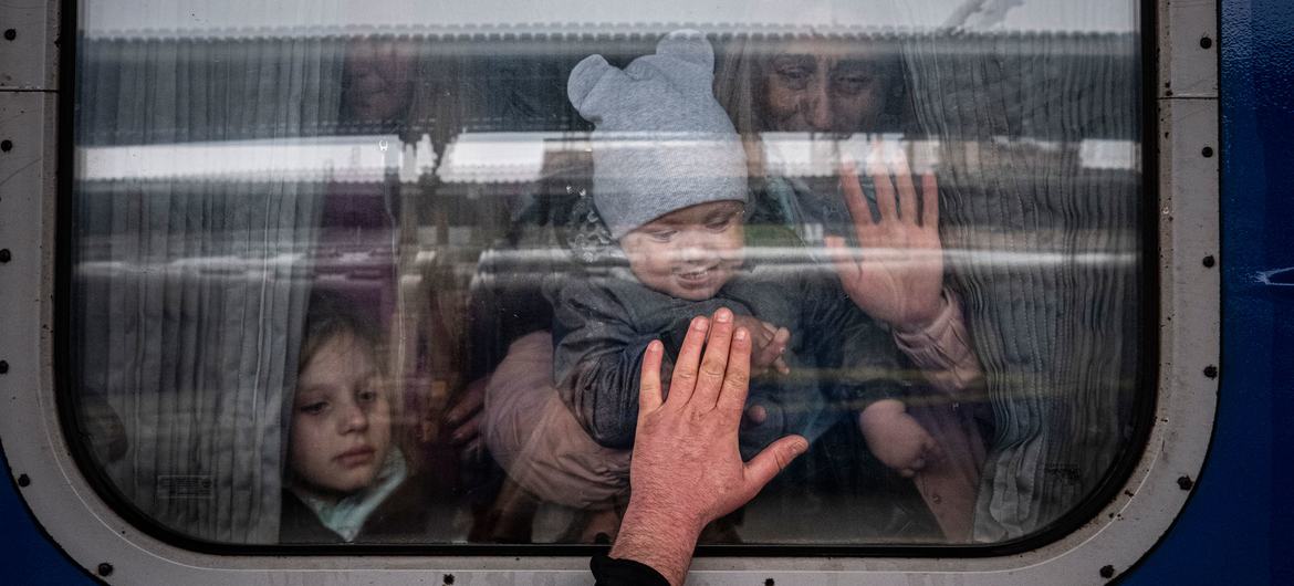 Em Kharkiv, na Ucrânia, um homem coloca a mão na janela de um vagão de trem enquanto se despede de sua esposa e filhos antes de partirem em um trem especial de evacuação.