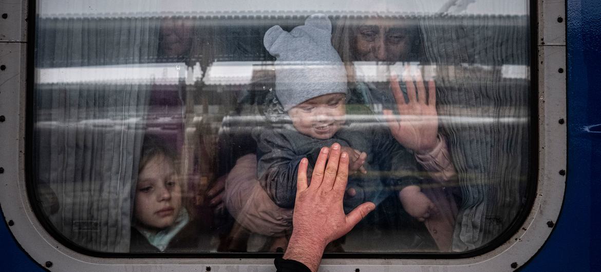 In Kharkiv, Ukraine, a man places his hand to the window of a train car as he says goodbye to his <a href=