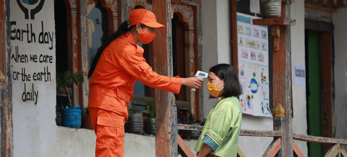 一名“和平卫士”志愿者在接种中心门口为前来接种新冠疫苗的居民测量体温。