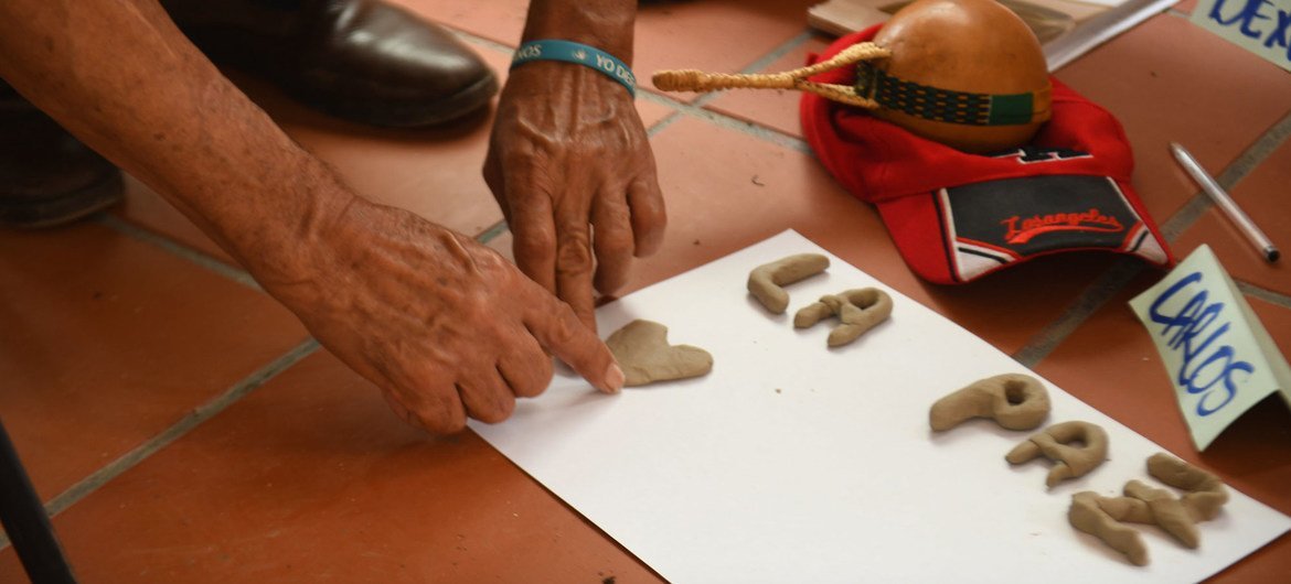 Participante en un programa de reconciliación de Colombia escribe la palabra paz.