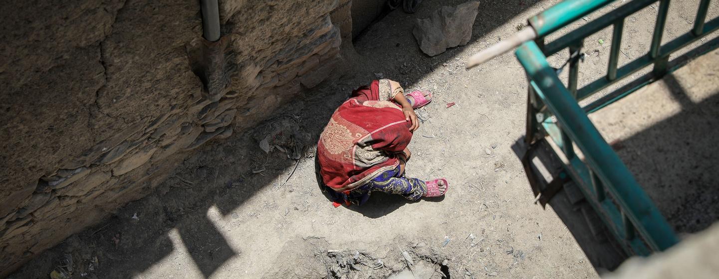 Zarlakht sits in the street next to her destroyed house in the Afghanistan earthquake, disoriented.