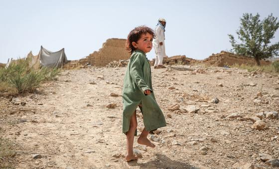 A young boy walks up a hill to return to his old home, destroyed by an earthquake in Afghanistan in June 2022.