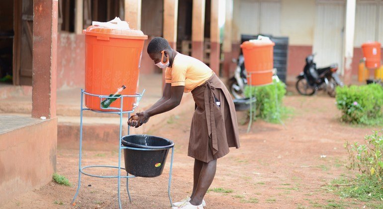 Jovem em Gana lava as mãos antes de voltar para a aula.