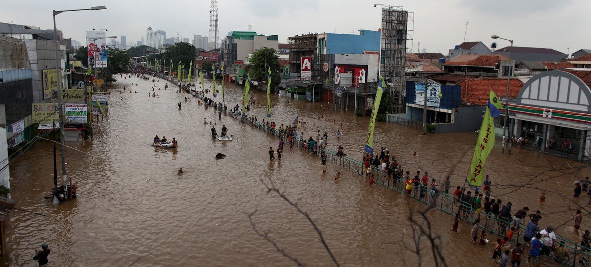 Children and adults make their way, on foot and in rafts, through flooded streets to higher ground at a highway median, in eastern Jakarta, Indonesia. (January 2013)