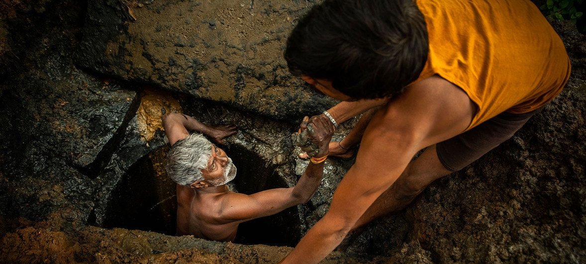 A latrine emptier is lifted out of a pit in Bangalore, India.