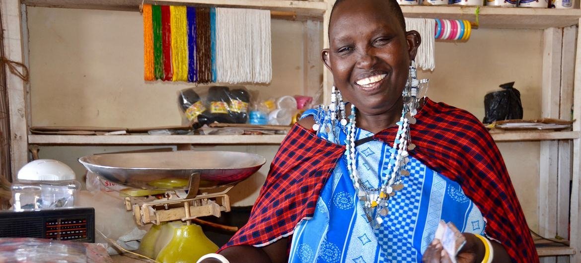 तंज़ानिया के अरूषा में, एक गाँव बाज़ार स्थित अपनी एक दुकान में काम करते हुए एक महिला उद्यमी.