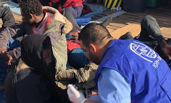 Migrantes que retornaram à costa na Líbia recebem apoio de trabalhadores humanitários da OIM.