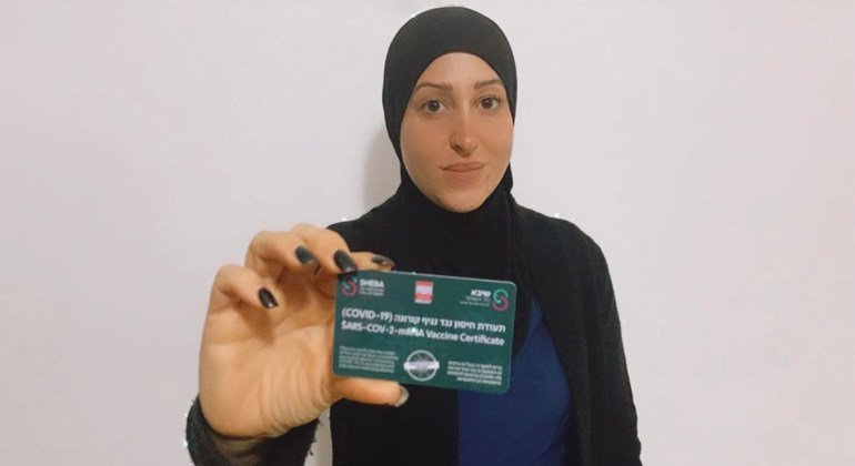 سيّدة عربية من الداخل الإسرائيلي تبرز بطاقة كوفيد-19 التي تشير إلى تلقيها اللقاح ضد الفيروس.