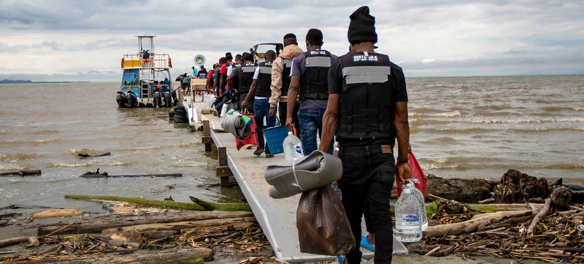 Migrantes entram em barco no Golfo de Uraba, Colômbia. 