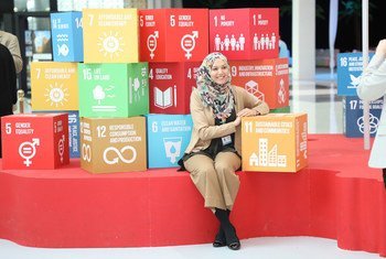 Une jeune femme assise devant les 17 Objectifs de développement durable. La question du financement du développement est plus que jamais importante alors que le monde répond à la pandémie de Covid-19 et doit préparer la reprise. 