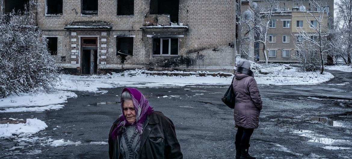 Pessoas caminham próximas a um prédio destruído em Donetsk, Ucrânia. 