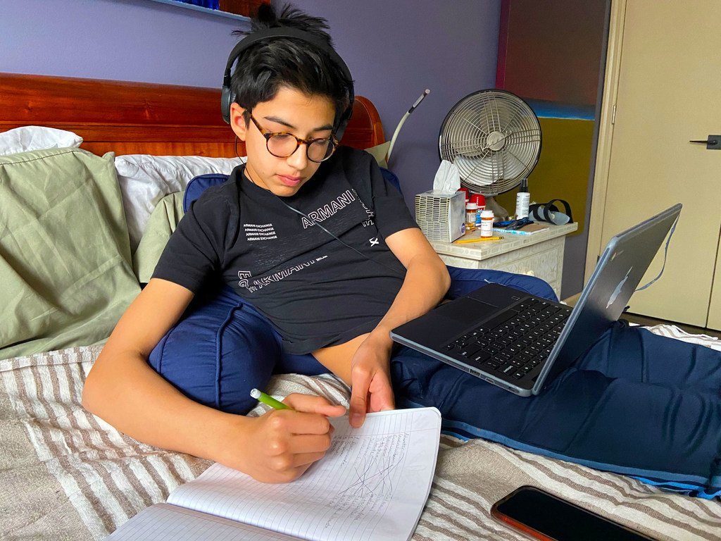 在纽约冠状病毒疫情暴发期间，这名十四岁的男孩在家中通过网络网上学，而他的父母进行远程办公。