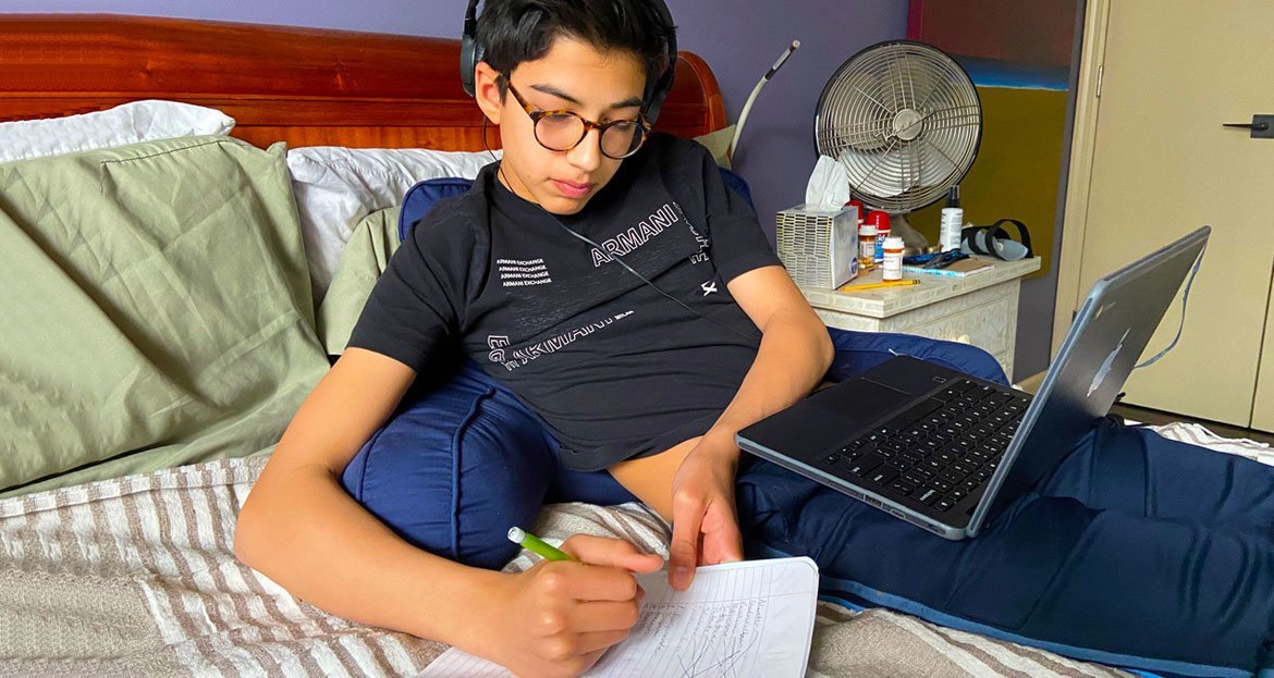 在纽约冠状病毒疫情暴发期间，这名十四岁的男孩在家中通过网络网上学，而他的父母进行远程办公。