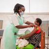 यूगाण्डा में एक स्वास्थ्य केन्द्र पर, एक नर्स एक महिला को कोविड वैक्सीन का टीका लगाते हुए.