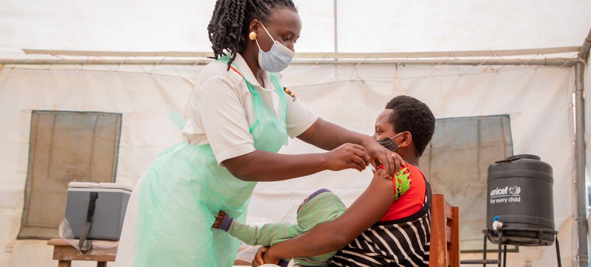 A nurse administers the COVID vaccine to a woman in a health centre in Uganda.