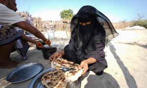 A woman baking bread at her shelter in Khanfar District, Yemen.