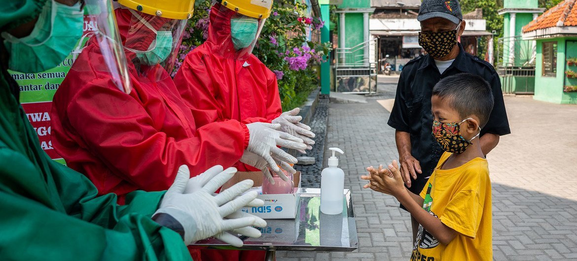 العاملون الصحيون يشرحون طريقة غسل اليدين بشكل صحيح لطفل في مركز صحي مجتمعي في وسط جافا، بإندونيسيا.