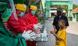 العاملون الصحيون يشرحون طريقة غسل اليدين بشكل صحيح لطفل في مركز صحي مجتمعي في وسط جافا، بإندونيسيا.