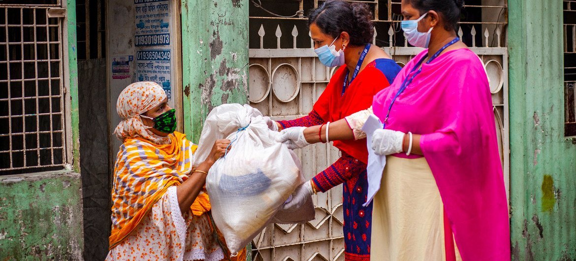 Development workers hand over relief aid to a woman amid the COVID-19 pandemic in Dhaka, Bangladesh.