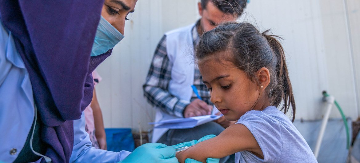 A young girl receives a vaccination against polio and measles in Iraq after fleeing conflict in northeastern Syria.