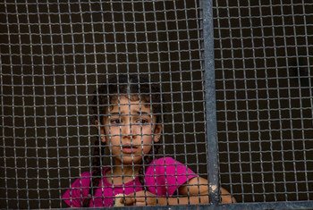 Una niña siria mira a través de una ventana desde el albergue para desplazados a donde llegó con su familia.