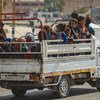 Na Síria, mulheres e crianças sendo transportadas na traseira de um caminhão, após fugirem da violência.