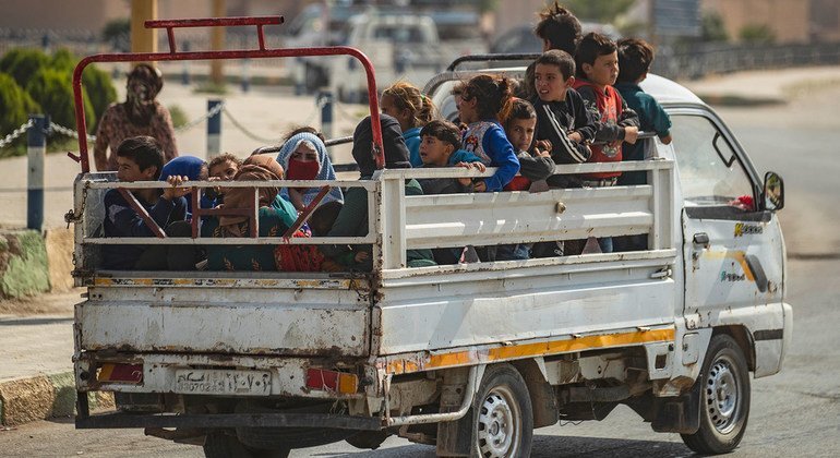 Na Síria, mulheres e crianças sendo transportadas na traseira de um caminhão, após fugirem da violência.