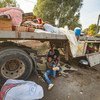 2019年10月11日，在阿拉伯叙利亚共和国，逃离不断升级的暴力的拉斯艾因流离失所者抵达塔尔塔梅尔时，一名妇女和儿童坐在一辆卡车下面。