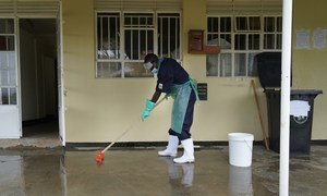 A staff member at a heath centre in Uganda cleans the floor using a mixture of chlorine and water to prevent infections. Proper water, sanitation and hygiene services at health facilities are vital to protect populations from infections.