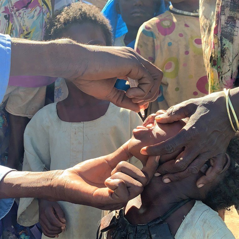 أمٌّ تمسك ابنها البالغ من العمر 3 سنوات، وهو يأخذ لقاح شلل الأطفال في كارا، جنوب جبل مرَّة 