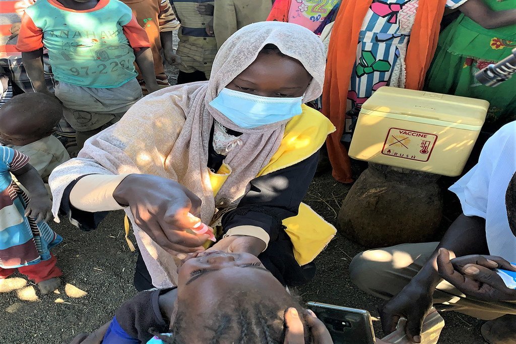 إحدى المُروَّجات لحملة التطعيم، أثناء إعطائها موناسا محيي الدين، ذات العامين، لقاح شلل الأطفال في غورلانغ بانغ، جنوب جبل مرَّة
