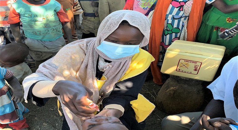 إحدى المُروَّجات لحملة التطعيم، أثناء إعطائها موناسا محيي الدين، ذات العامين، لقاح شلل الأطفال في غورلانغ بانغ، جنوب جبل مرَّة
