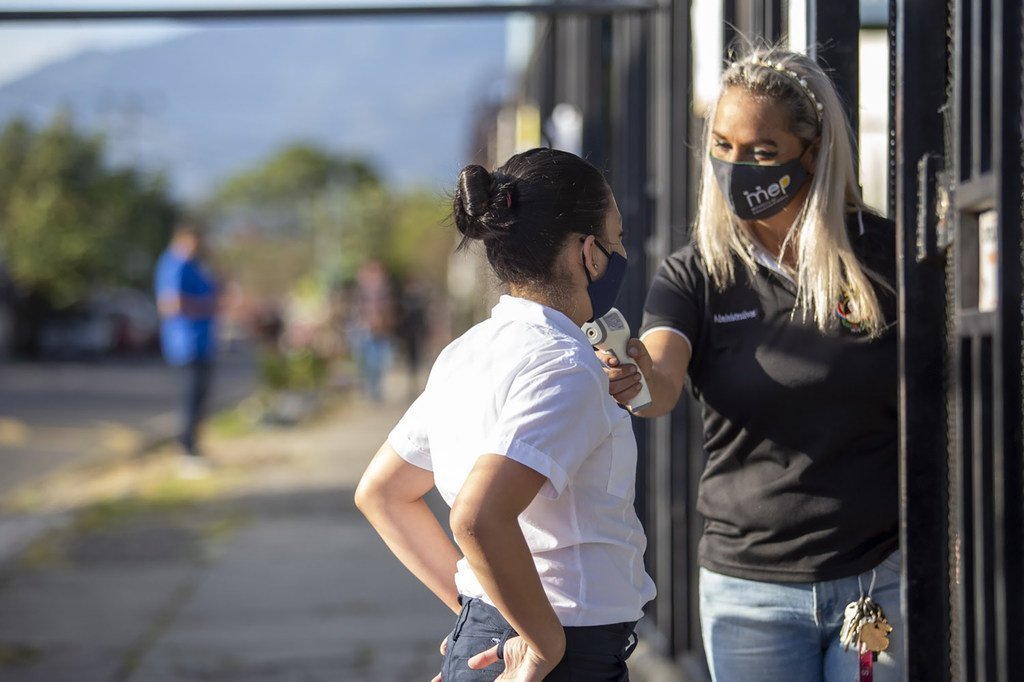 Una maestra le toma la temperatura a Keisy, estudiante ejemplar, antes de que entre a la escuela, en Costa Rica.