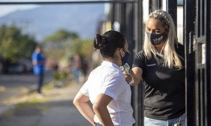 Una maestra le toma la temperatura a Keisy, una estudiante en la escuela Leon XIII, ublicada en el área de exclusión social en San José, la capital de Costa Rica, antes de entrar a la escuela.