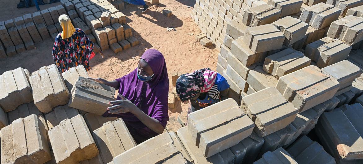 Une femme empile de nouvelles briques dans la briqueterie de Ouallam, dans un camp pour personnes déplacées et réfugiées au Niger.