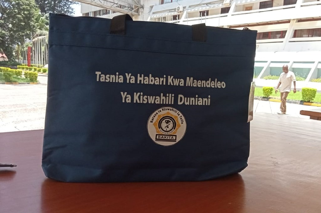 Mfuko wa kubebea vitu vya bluu wenye maandishi na nembo umewekwa kwenye meza ya mbao nje.