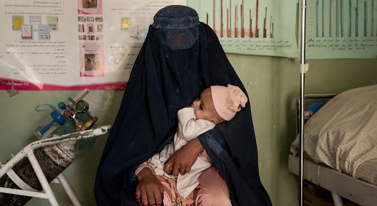Mulher leva sobrinha desnutrida para ser tratada em clínica no Afeganistão. 