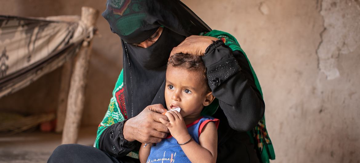 也门拉赫杰，一名妇女和她的儿子坐在临时搭建的家中。