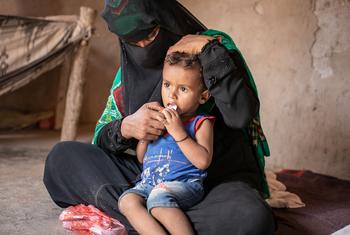 A woman sits with her son at the family's makeshift home in Lahj, Yemen.