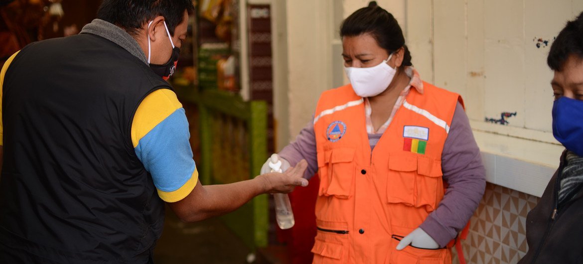 Una mujer aplica desinfectante de manos a un cliente a la entrada de un mercado municipal en la ciudad guatemalteca de San Marcos.